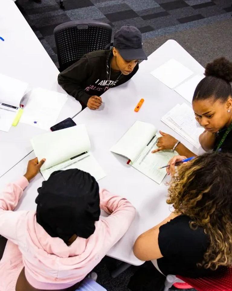 A picture of some of urban circle sat around with pen and paper looking like their planning something