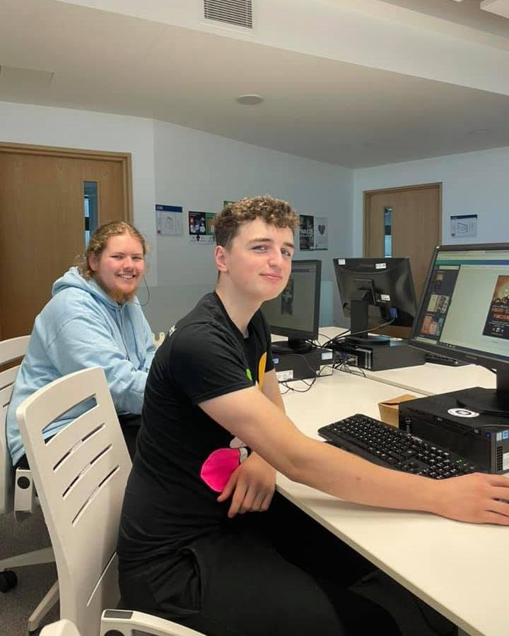 2 boys sat in front of computers.