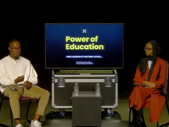 A picture of 2 people on stage holding a talk about the power of education